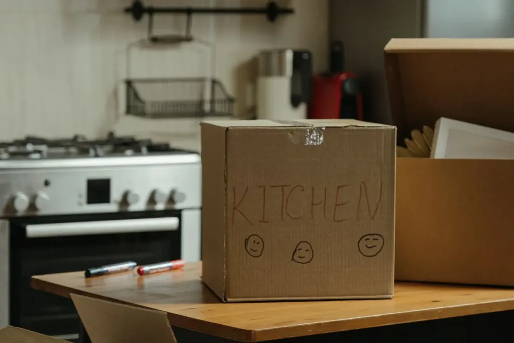 Cajas de mudanza en una cocina junto al horno, con pequeños electrodomésticos al fondo