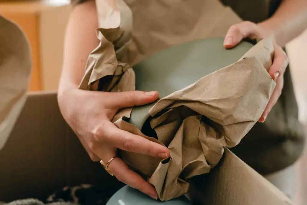 Manos envolviendo un plato en papel antes de guardarlo en la caja
