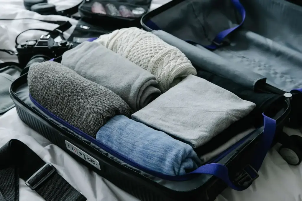Maleta abierta sobre la cama con ropa enrollada para los primeros días