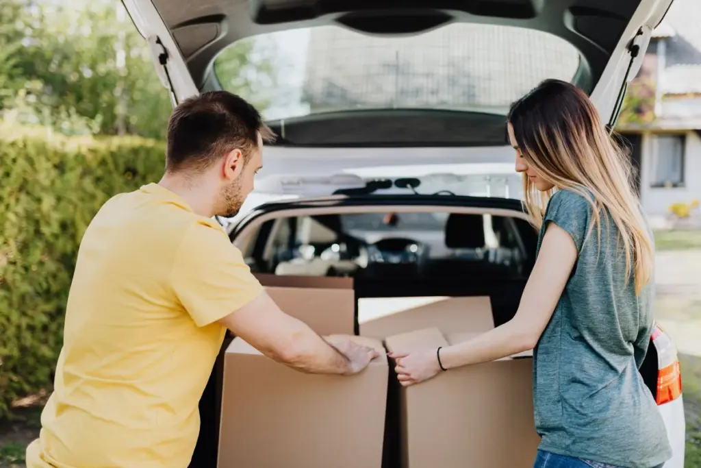 Pareja cargando cajas de mudanza en el maletero de un coche