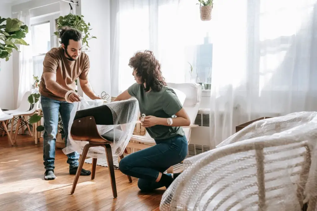Pareja envolviendo una silla con plástico de burbujas antes de la mudanza