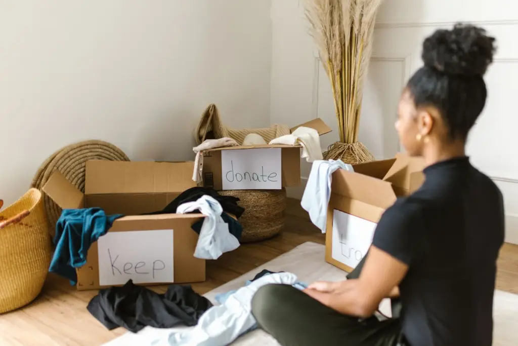 Persona separando ropa en cajas para guardar, donar y tirar